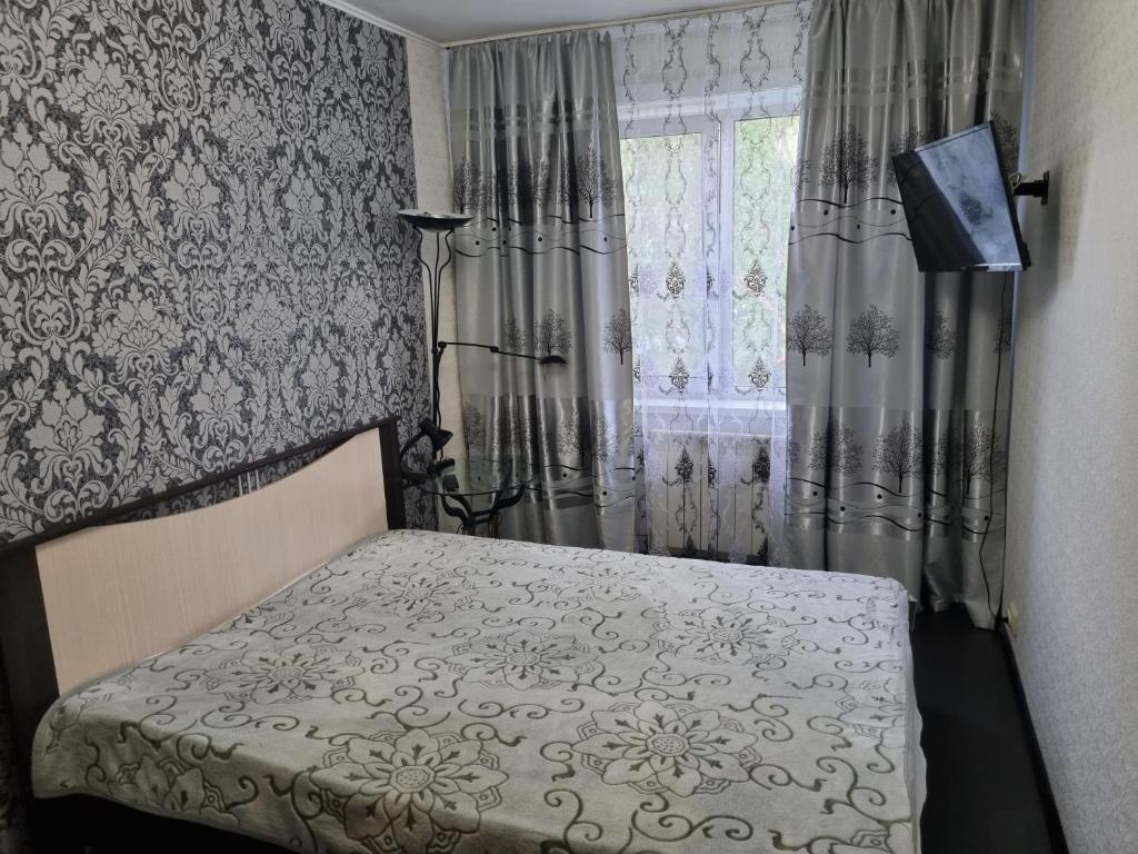 ユジノ・サハリンスクにあるДвухкомнатная квартираのベッドルーム1室(ベッド1台付)、窓(カーテン付)