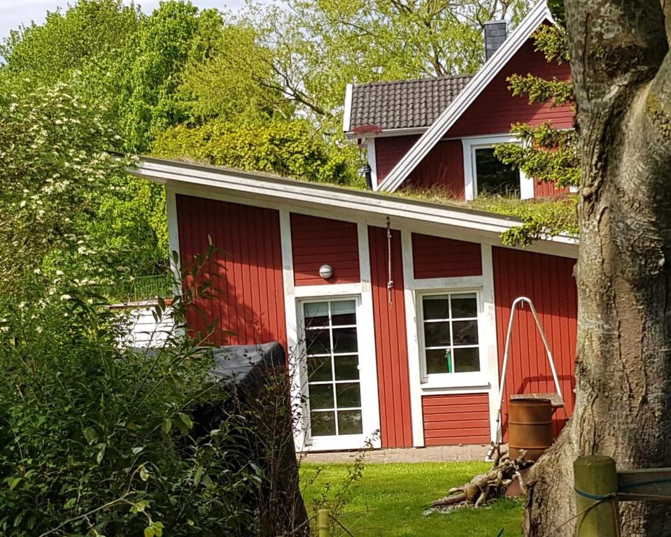 uma casa vermelha com janelas brancas e uma árvore em An der Schafsweide em Aukrug