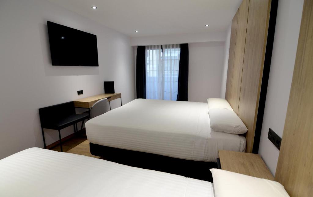 a hotel room with two beds and a desk at UVE Marcenado in Madrid