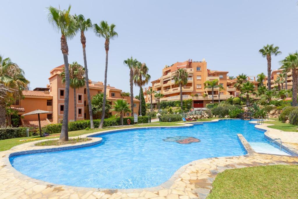 a swimming pool in a resort with palm trees and buildings at Apartment 925 in Marbella