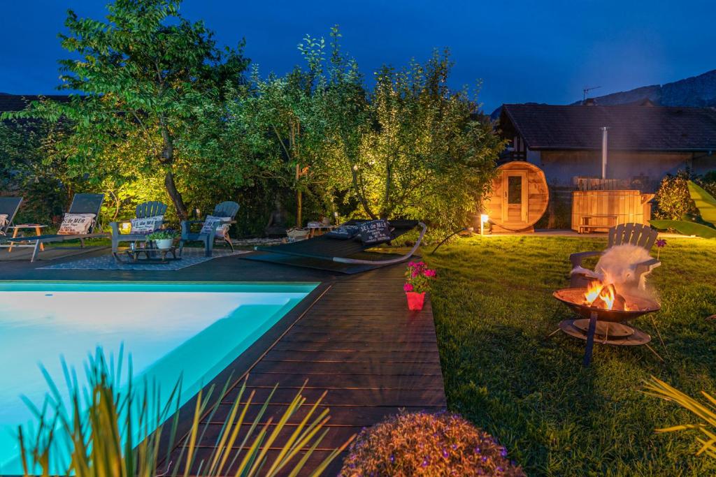a backyard with a fire pit next to a swimming pool at Hygge Lodge Annecy in Doussard