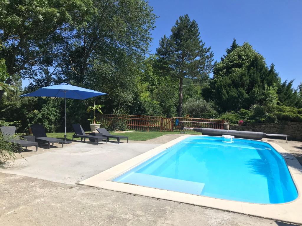 - une piscine avec un parasol, deux chaises, une table et un parasol dans l'établissement Gites de Montcabirol, à Mirepoix