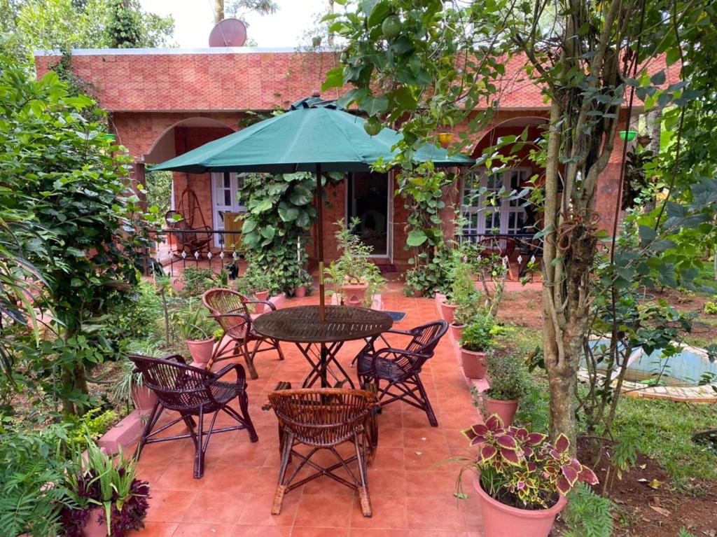 une terrasse avec une table, des chaises et un parasol dans l'établissement Yelagiri Villa, à Yelagiri