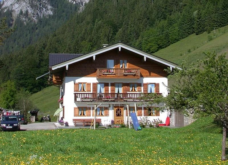 a large wooden house with a balcony on a mountain at Fluchthäusl Ferienwohnung in Ramsau