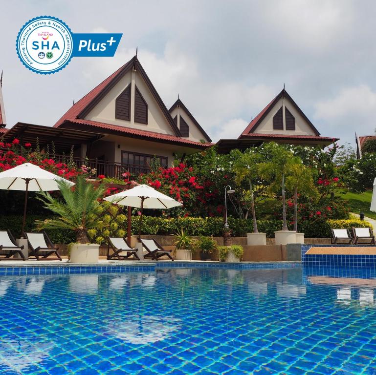 ein Resort mit einem Pool mit Stühlen und Sonnenschirmen in der Unterkunft Baan KanTiang See Villas - SHA Extra Plus in Ko Lanta