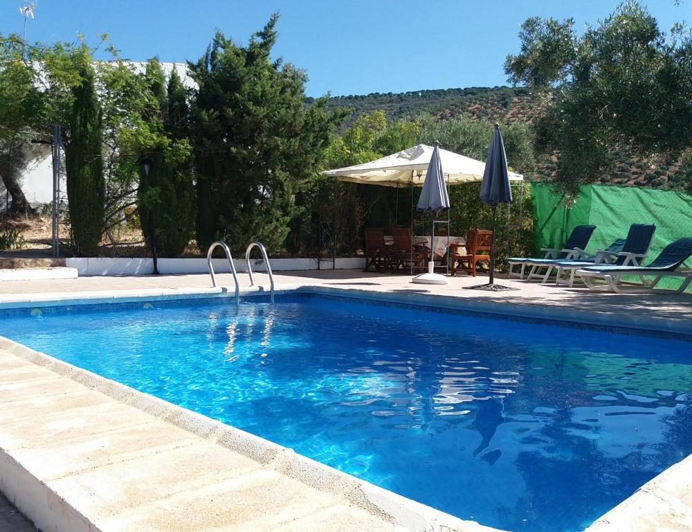 una piscina con ombrellone, sedie e tavolo di Cortijo "Era Grande 2" a Cordoba