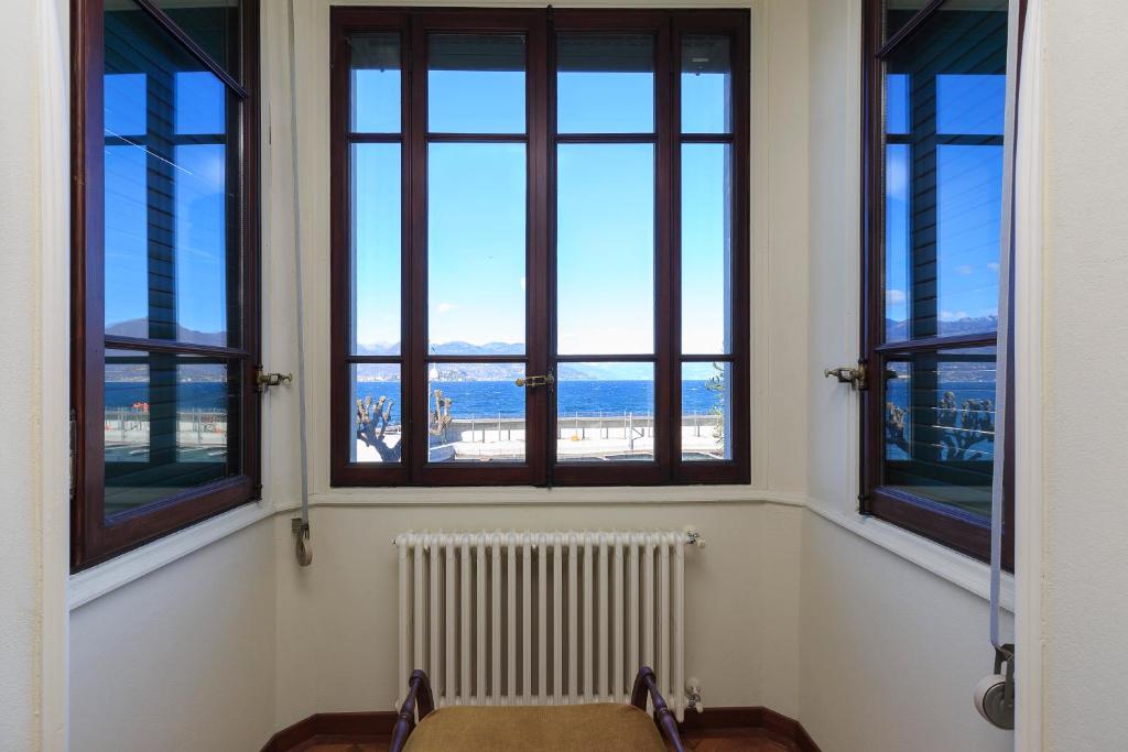 une chambre avec trois fenêtres et un radiateur dans l'établissement Palazzo BellaVista by Impero House, à Stresa