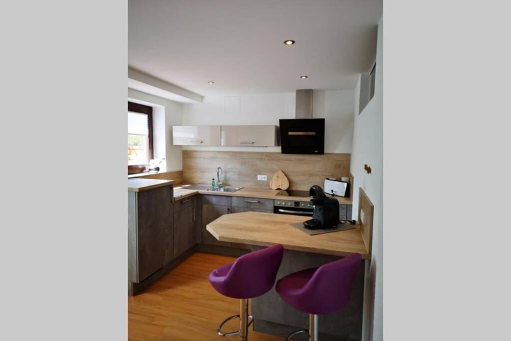 a kitchen with purple stools and a counter at Ferienwohnung Susanne, Losheim am See in Wahlen
