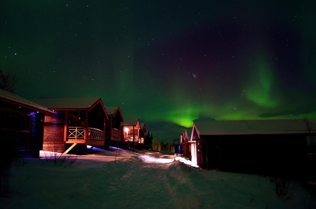 an image of the aurora in the sky over a cabin at Kåppas Cabin Village in Björkliden