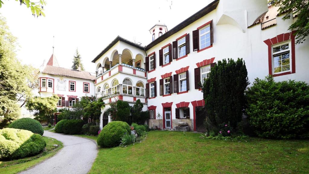 Casa blanca grande con detalles en rojo y patio en Castel Campan en Bressanone