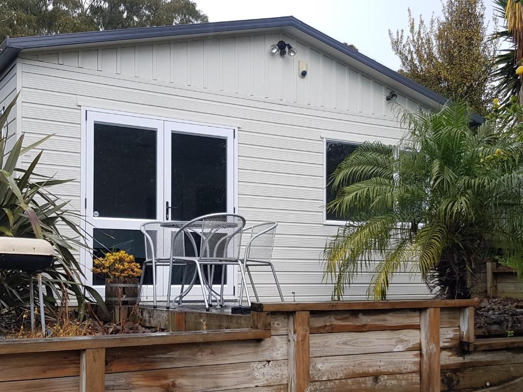 a tiny house with chairs on a deck at Affordable, Spacious, Bright, Warm, Unit in Central Whangarei in Whangarei
