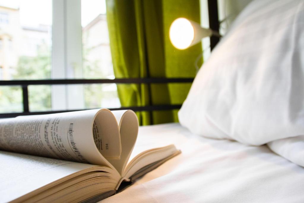 an open book on a bed with a pillow at Hostel Mandarinka in Prague