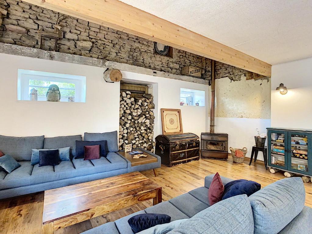 a living room with a blue couch and a stone wall at Gîte les Gambettes in Amel-sur- lʼÉtang