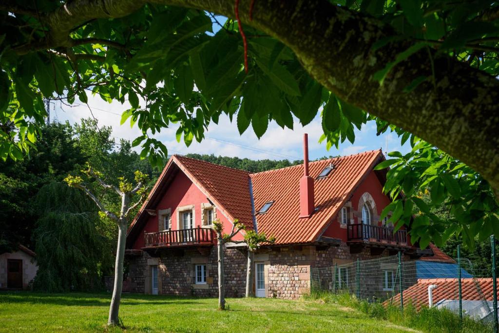 uma casa com um telhado vermelho e um quintal em Complejo Puente Romano em Entrambasaguas