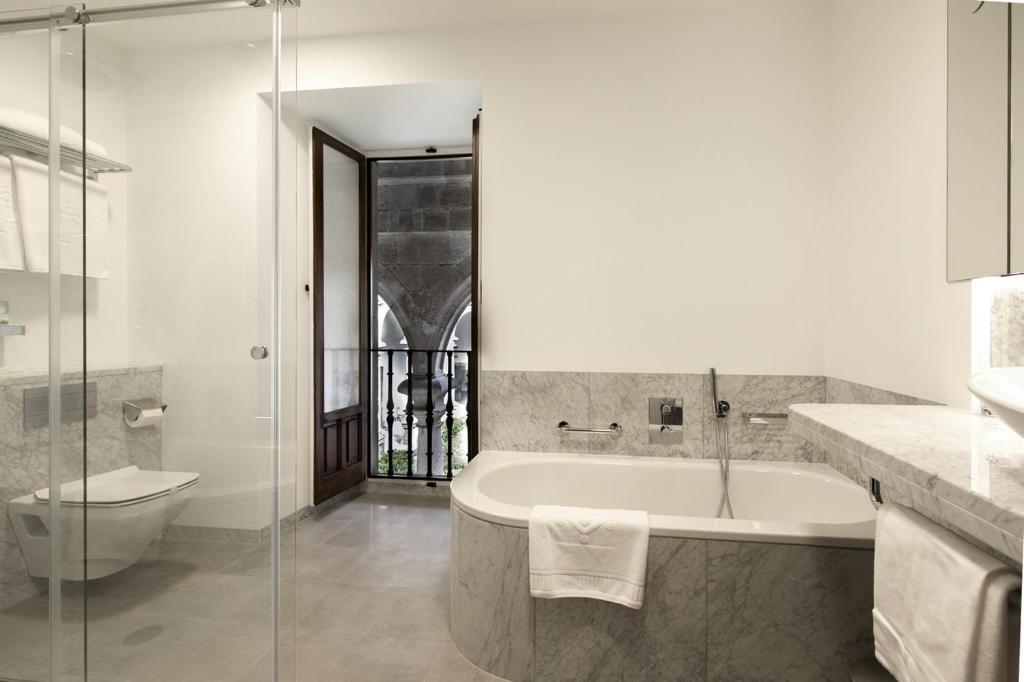 a bathroom with a tub and a toilet and a sink at Parador de Santiago - Hostal Reis Catolicos in Santiago de Compostela