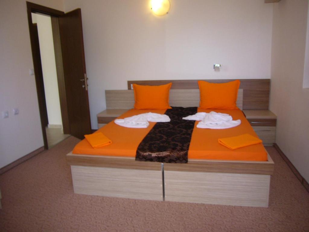 a bed with orange pillows and towels on it at Family Hotel Golden Lion in Primorsko