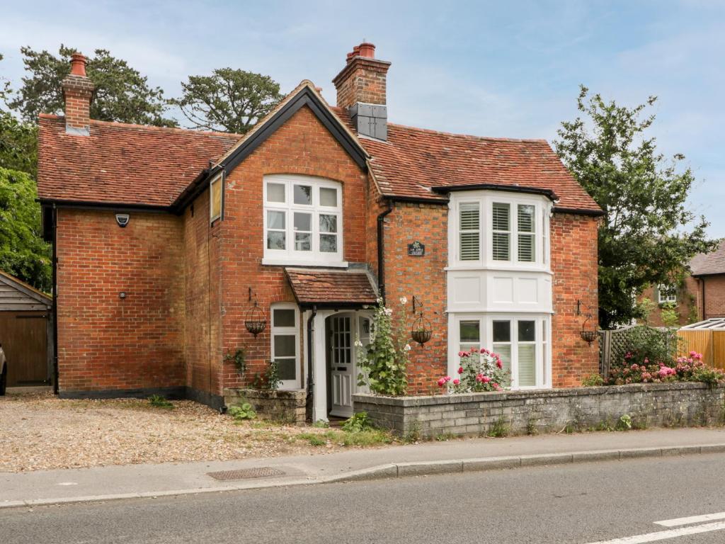 a red brick house with white windows on a street at Oakapple Cottage in Lyndhurst
