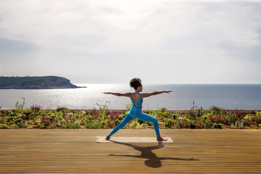 a woman doing a yoga pose in front of the ocean at Six Senses Ibiza in Portinatx