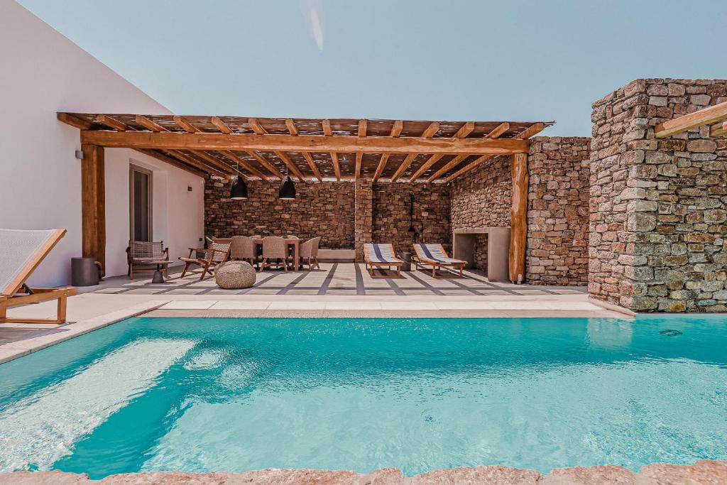 a swimming pool in front of a stone building at Amarelo Suites in Klouvas