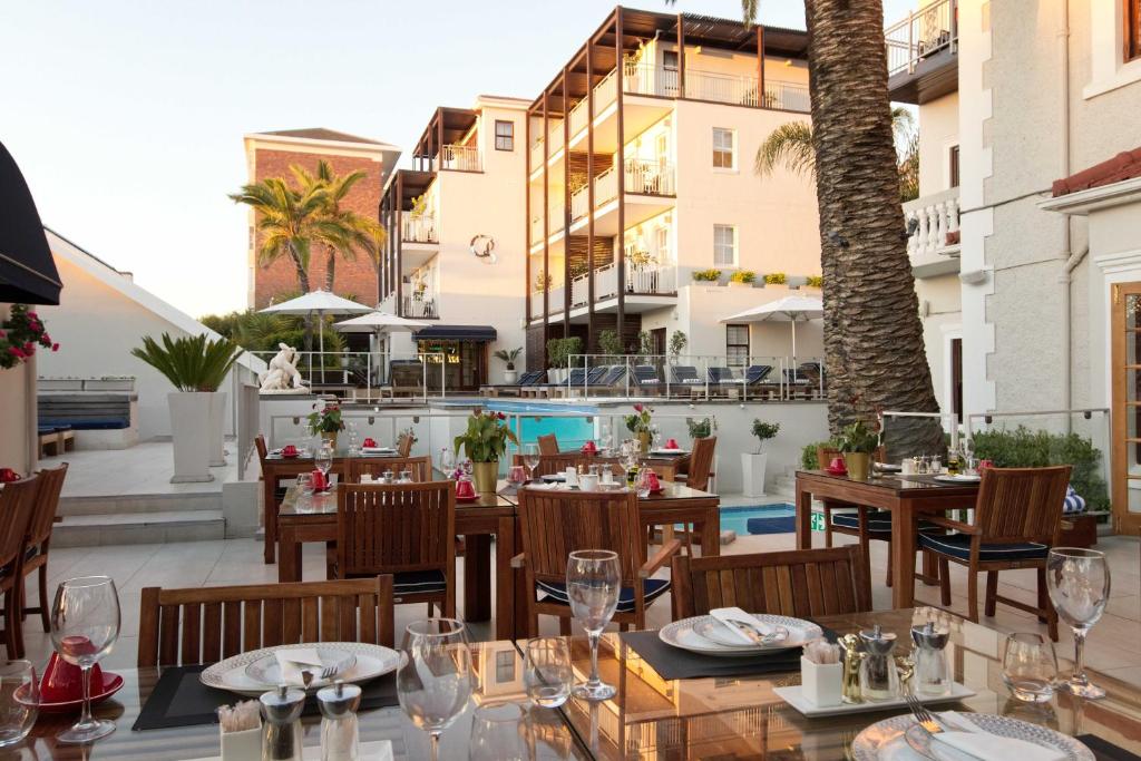 un restaurante con mesas y sillas y una piscina en The Glen Boutique Hotel & Spa en Ciudad del Cabo