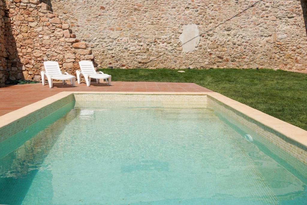 two white chairs sitting next to a swimming pool at Casa Rural La Fàbrega in Aiguamurcia