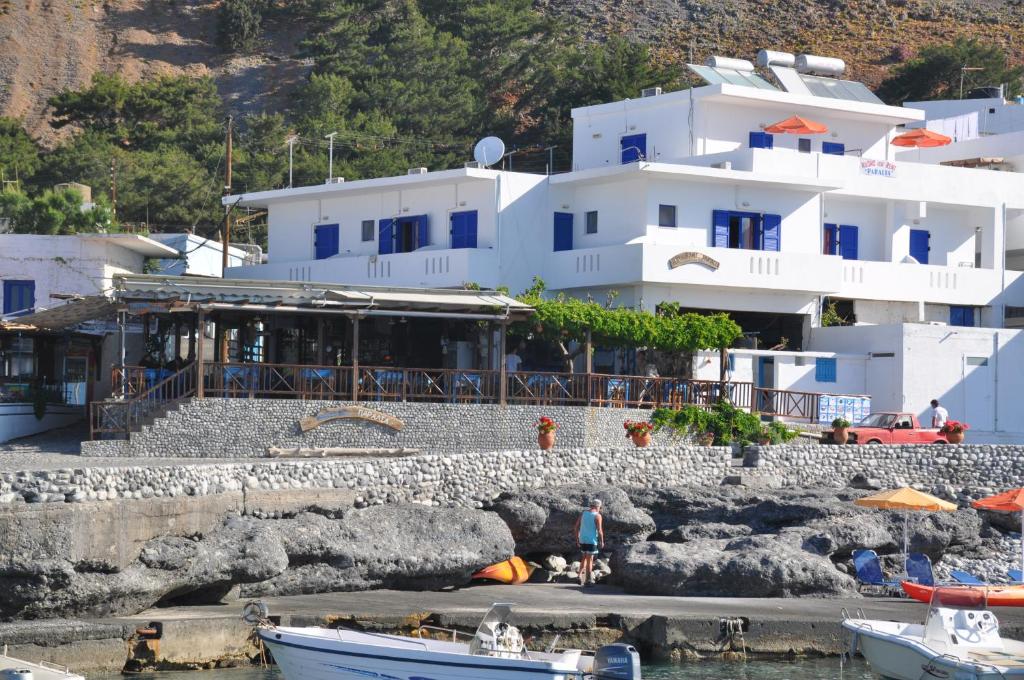 a large white building with boats in the water at Paralia guest house in Agia Roumeli