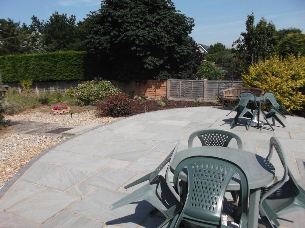 a patio with green chairs and a table and chairs at Sea Shells in Greatstone