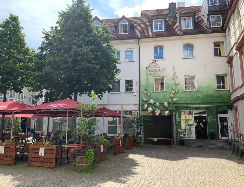 ein großes weißes Gebäude mit roten Sonnenschirmen im Innenhof in der Unterkunft Altstadthotel Arte in Fulda