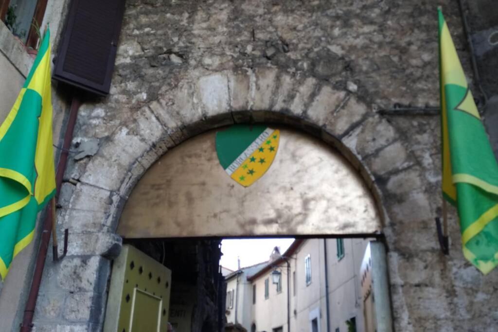 un arco en un edificio de piedra con una bandera en La casa all'Arco, en Campiglia dʼOrcia