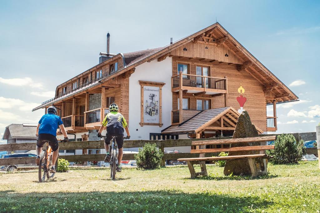 dwoje ludzi jeżdżących rowerami przed budynkiem w obiekcie Hotel-Gasthof Deixelberger w mieście Wolfsberg