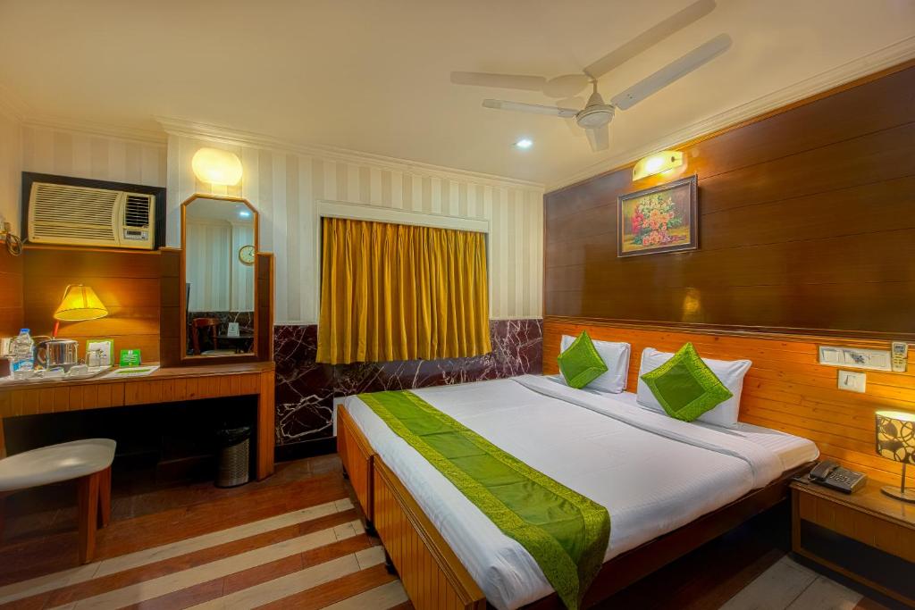 a bedroom with a bed and a desk and a mirror at Treebo Trend Green View in Kolkata