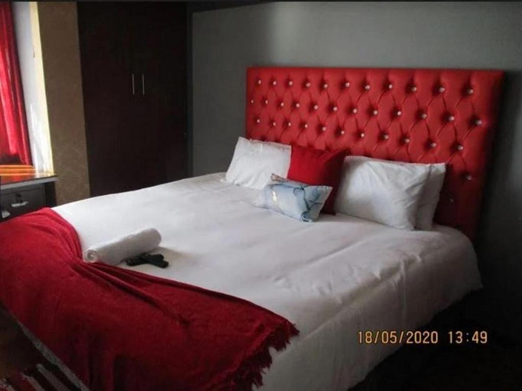 a bedroom with a large bed with a red headboard at Imimangaliso Guest House in Mthatha