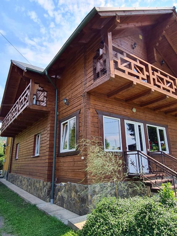 a wooden house with a balcony on the side of it at Приватна Садиба Потічок in Slavske