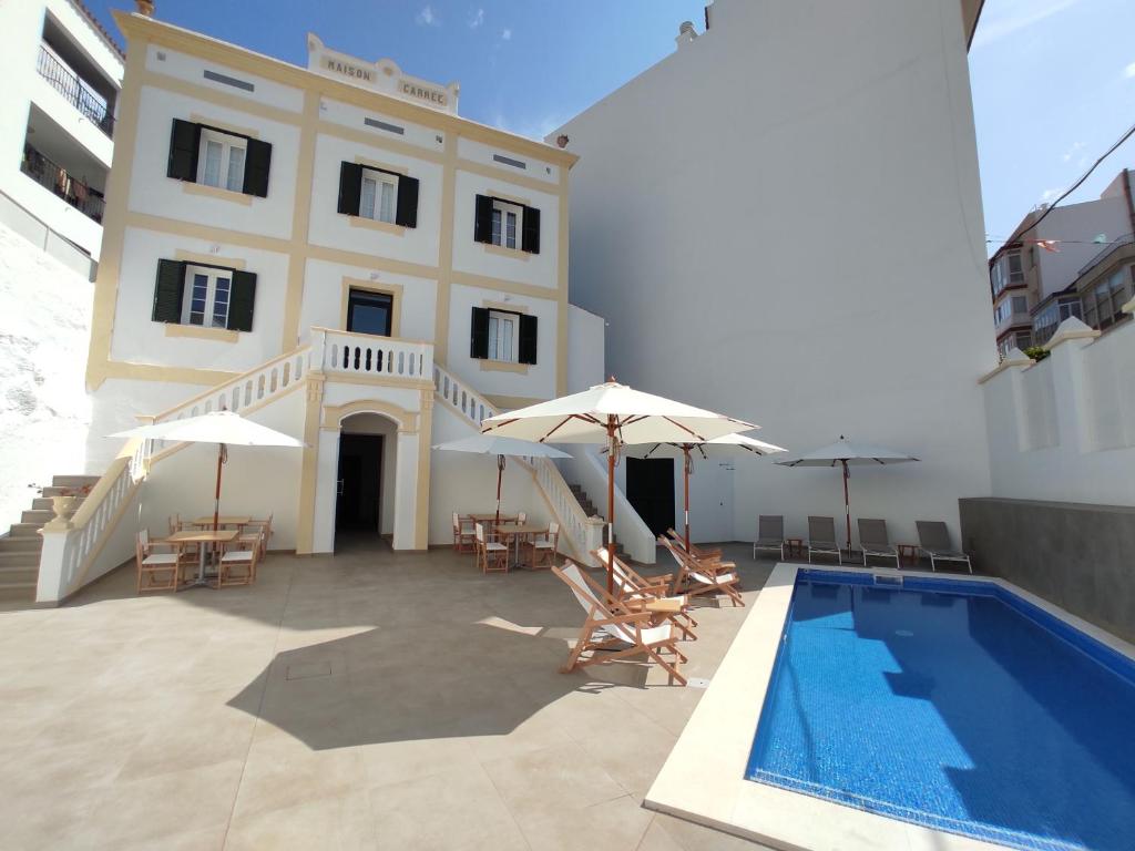 - une piscine avec des chaises et des parasols en face d'un bâtiment dans l'établissement Hotel Amano Maison Carrée, à Alaior