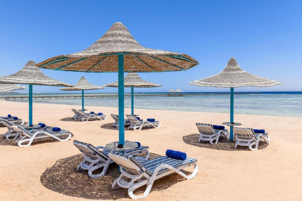 un grupo de sillas y sombrillas en una playa en Iberotel Redsina, en Sharm El Sheikh