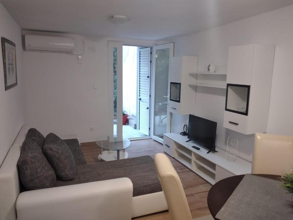uma sala de estar com um sofá e uma televisão em Apartman Ivano em Kaštela