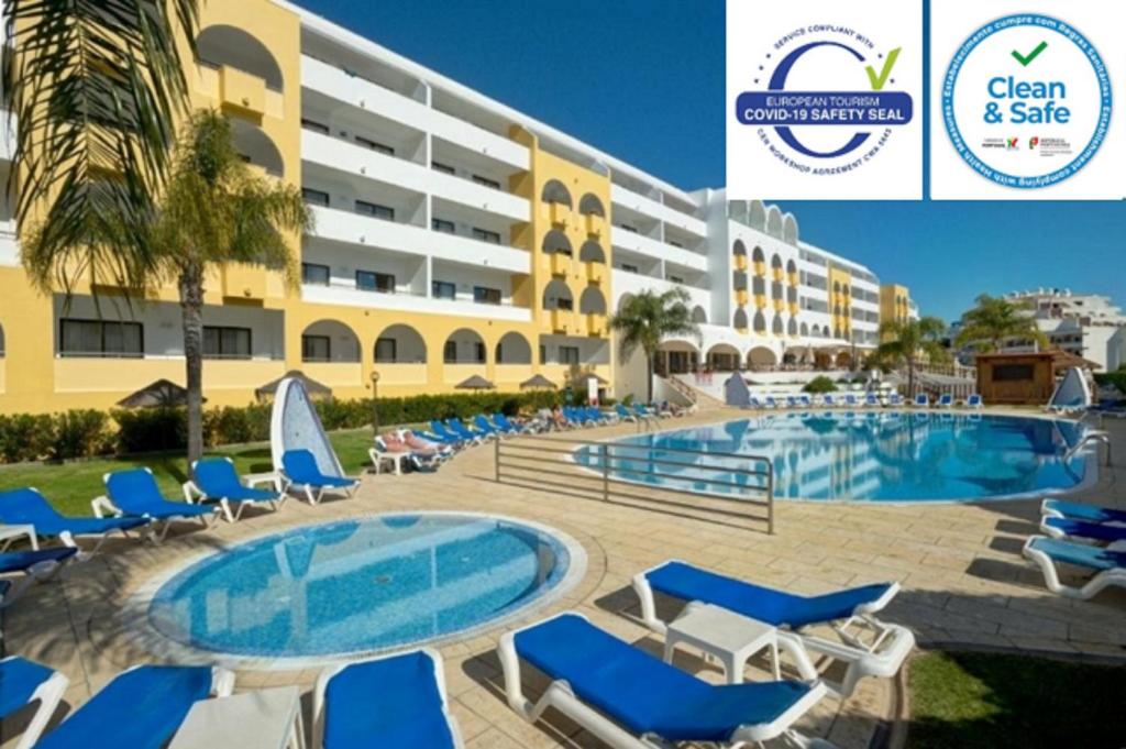 un complejo con piscina, sillas y un edificio en Aparthotel Paladim & Alagoamar, en Albufeira