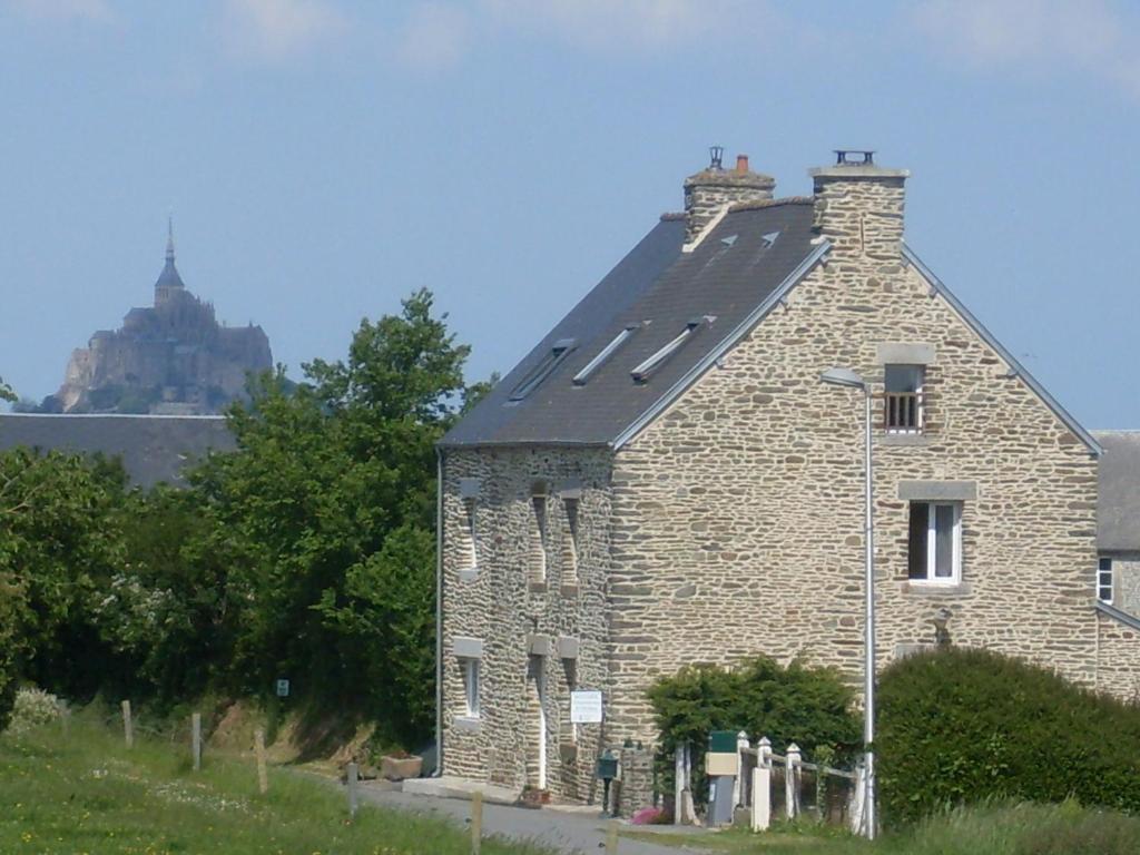 un vecchio edificio in mattoni con un castello sullo sfondo di Chambres D'hôtes au Saint Avit a Huisnes-sur-Mer