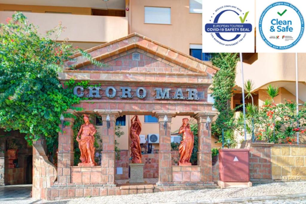 a statue of three women in front of a building at Choromar Apartments in Albufeira