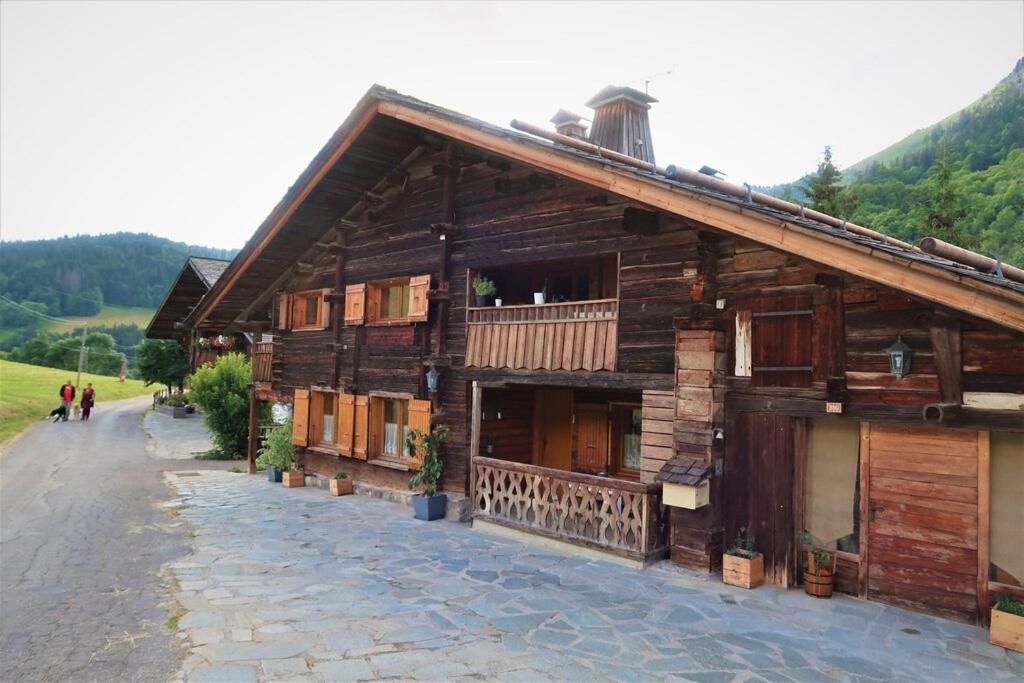 - un bâtiment en bois avec des personnes marchant devant dans l'établissement CHARMIEUX appartement en chalet typique, au Grand-Bornand