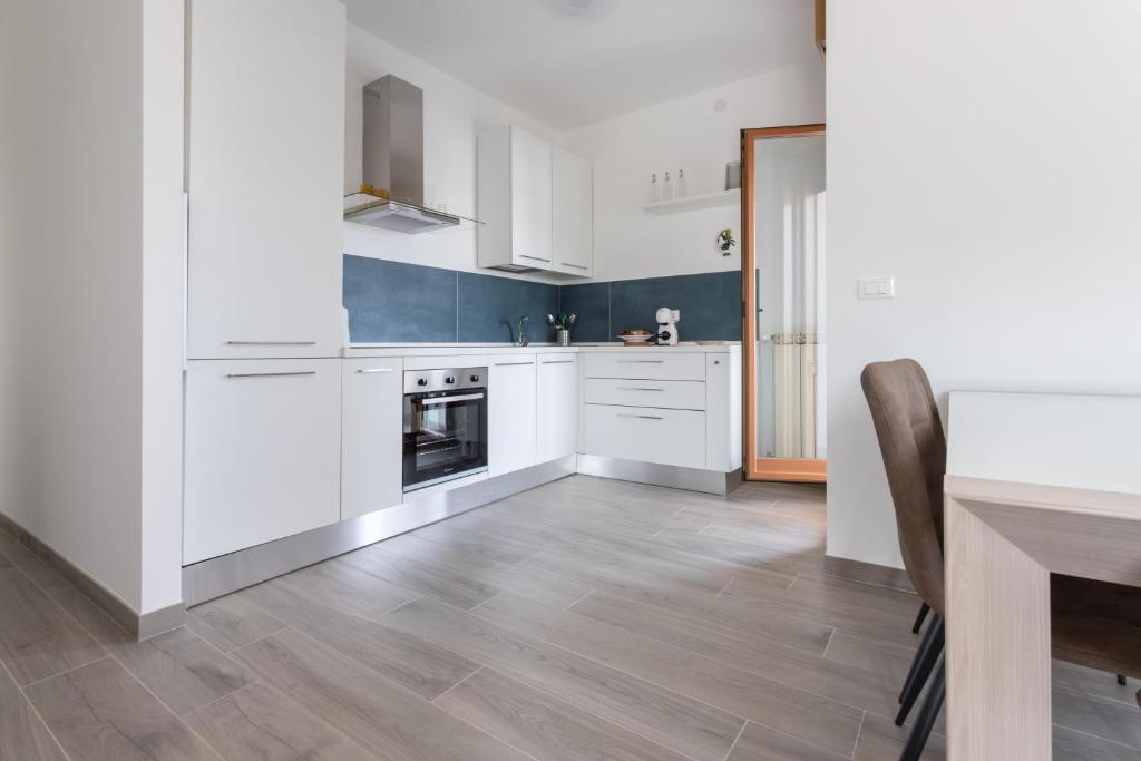 a kitchen with white cabinets and a wooden floor at A Casa di Lelia in Muggia