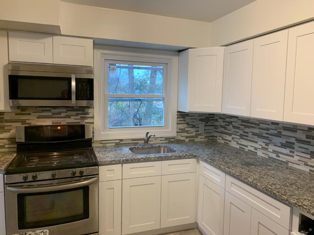 a kitchen with white cabinets and a sink and a window at Summer House in Long Branch
