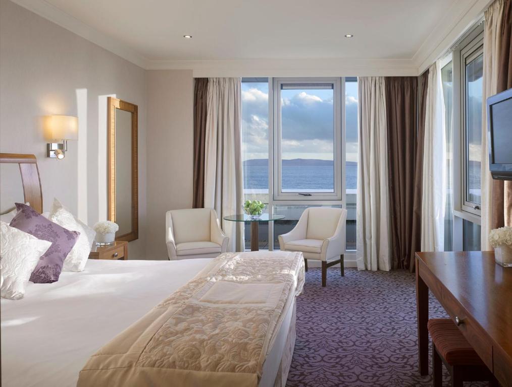 a hotel room with a bed and a desk and windows at Salthill Hotel in Galway