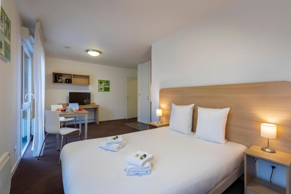 トロワにあるThe Originals Residence, Kosy Appart'hotels Troyes City & Parkの大きなベッドとデスクが備わるホテルルームです。