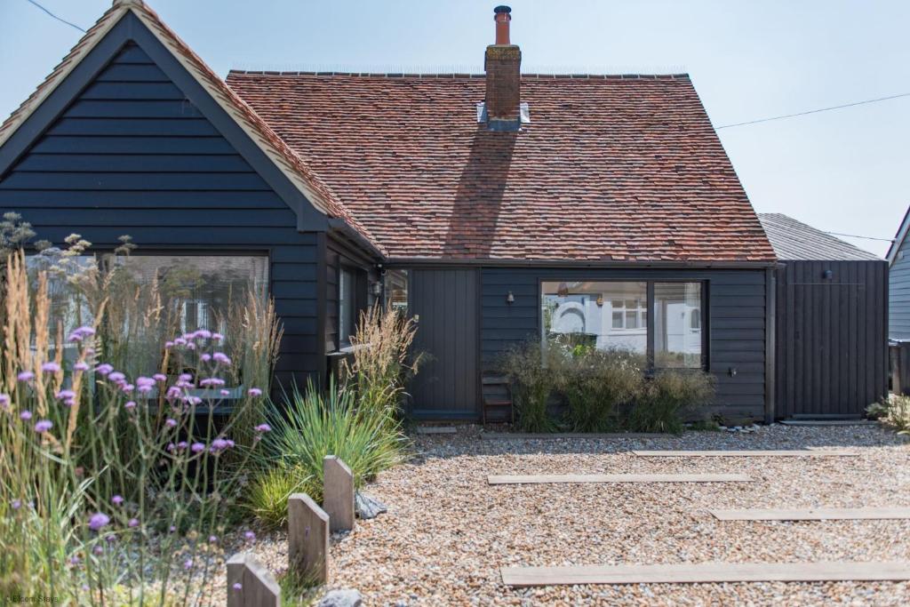 une maison noire avec un jardin en face dans l'établissement The Dunes by Bloom Stays, à Camber