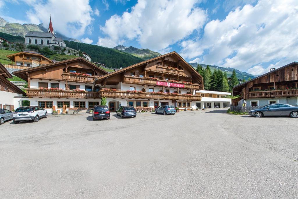 a large building with cars parked in a parking lot at Hotel Alpenrast in Riva di Tures