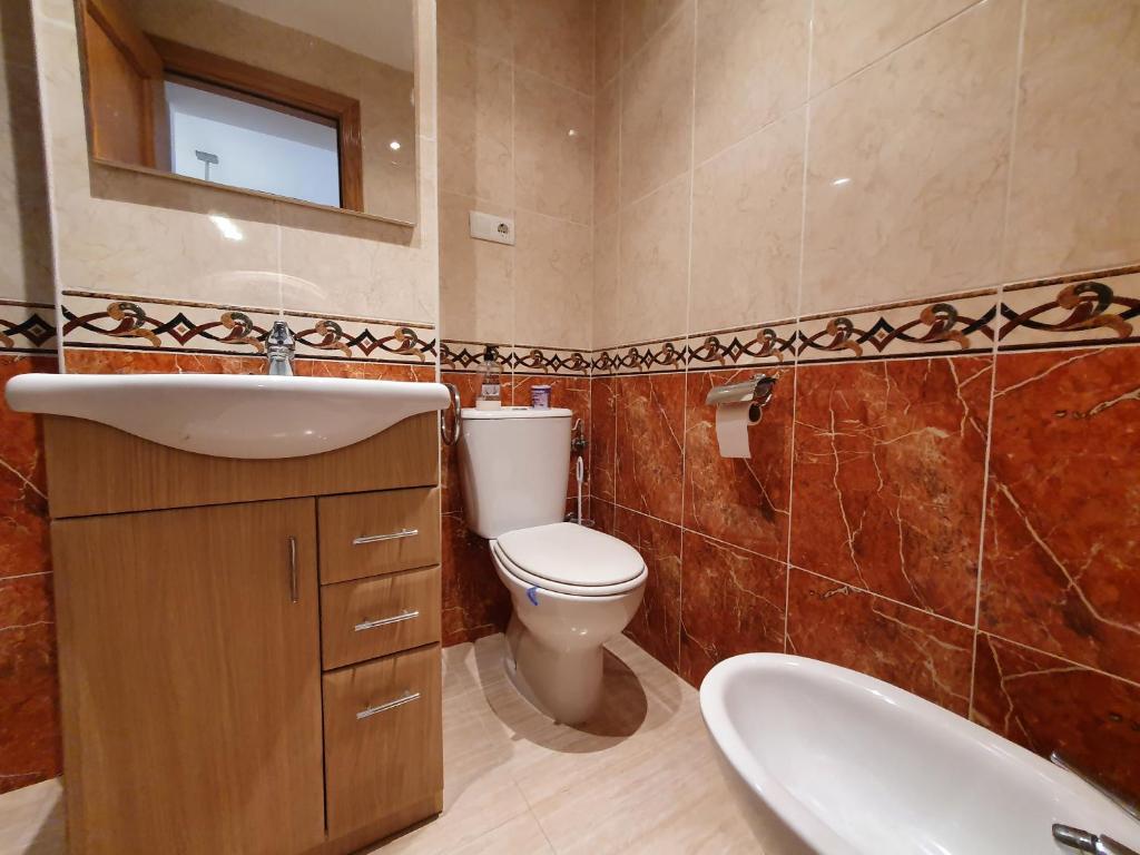 ein Badezimmer mit Waschbecken, Toilette und Spiegel in der Unterkunft Costa Caribe II Nº 1028 in Oropesa del Mar
