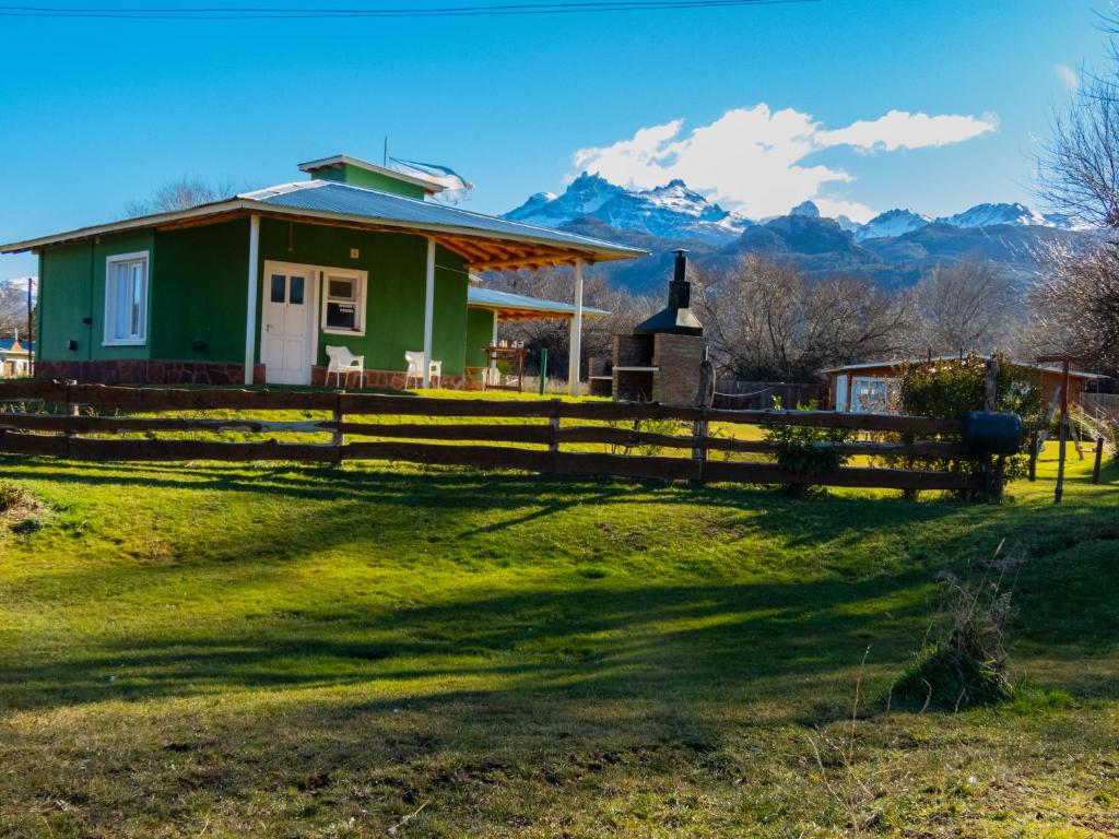 ein Haus mit einem Zaun und Bergen im Hintergrund in der Unterkunft Cabañas Rosa in La Aldea