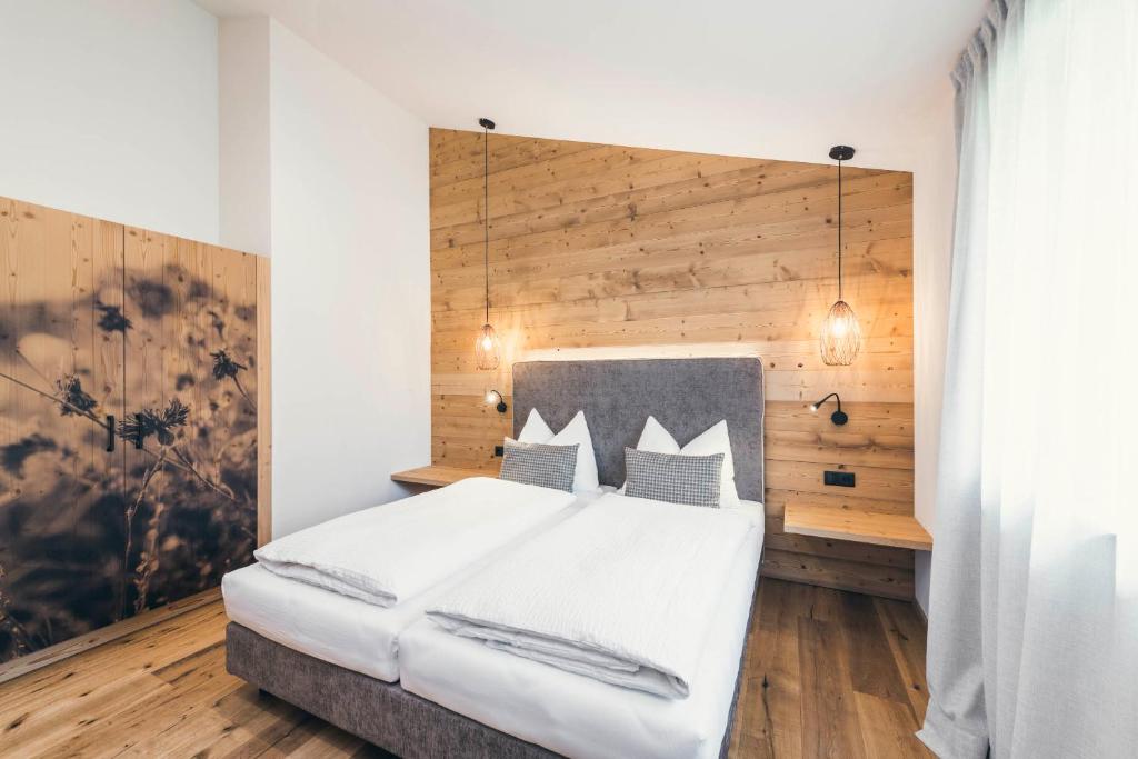 - une chambre avec un lit blanc et un mur en bois dans l'établissement Lichtung Woldererhof Auszeit, à Racines