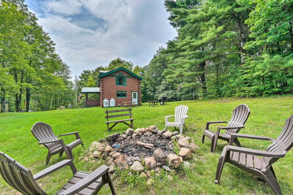 a group of chairs around a fire pit with a log cabin at Spacious Mtn Cabin on 7 Private Acres in Athol! in Athol